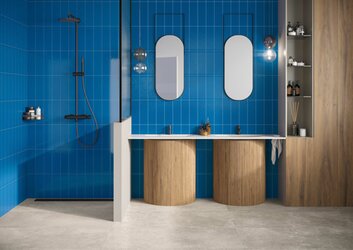 Dlažba imitující kámen Unika cenere na podlaze, modrý obklad Colors zaffiro na stěně v koupelně se zrcadlem a umyvadlý