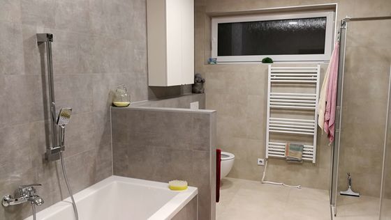 Koupelna zákazníka vypadá skvěle díky obkladům, dlažbě a také vhodně zvoleným zařizovacím předmětům a doplňkům. | Kombinací šedo-béžových tónů dlaždic v imitaci betonu vznikla elegantní koupelna čistých linií