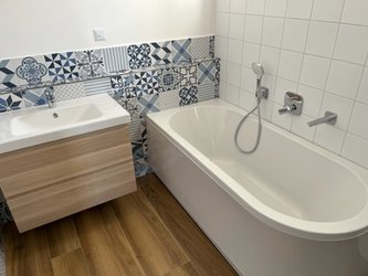 Designové obklady Moving blue v koupelně kolem umyvadla a vany + bílé obklady POP white