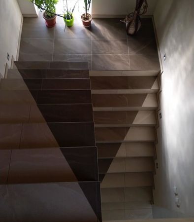 Schodiště s trojúhelníkovým prvkem vytvořeným z dlažby. | Dlažba napodobující kámen připomíná na schodišti zákazníka trojúhelník