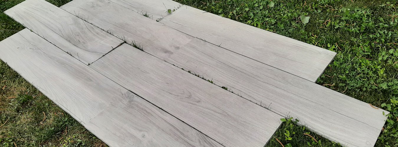 Venkovní dlažba Jurupa 02 Cool sv. šedá barva imitace dřeva položená na trávě